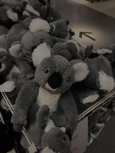 a bunch of stuffed koalas are stacked on top of each other in a bin