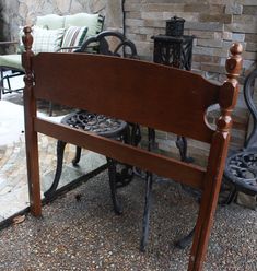 a wooden bed frame sitting in front of a brick wall next to chairs and tables