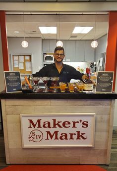 a man standing behind a counter filled with food and drinks in front of a mirror