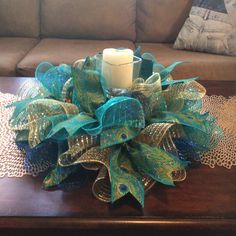 a candle is sitting on top of a table with blue and green ribbons around it