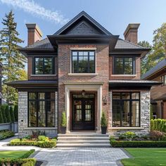 a large brick house with lots of windows and landscaping around the front door is shown