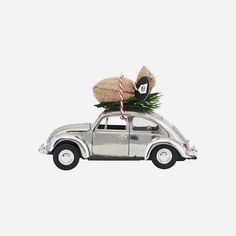 an old car with a christmas tree on the roof and two baskets on top, against a white background