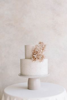 a three tiered white cake sitting on top of a table next to a wall