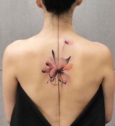 the back of a woman's neck with a flower tattoo on it