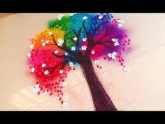 a colorful tree with white flowers painted on the bottom and purple, blue, green, yellow, red, orange, and pink