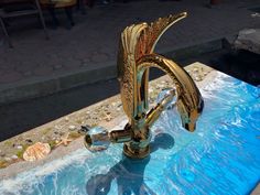 a gold faucet sitting on top of a blue table next to a pool