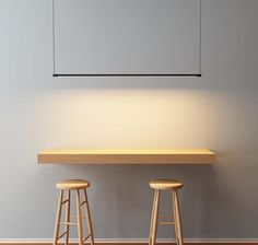 two stools sit in front of a table with a light on it and an empty board hanging above