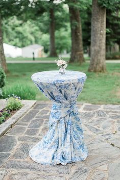 a blue and white table cloth draped over it's top on a stone patio