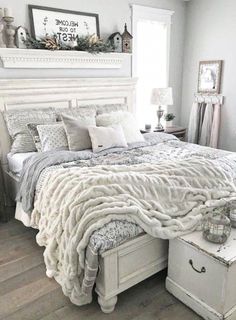 a white bed sitting in a bedroom next to a window covered in blankets and pillows