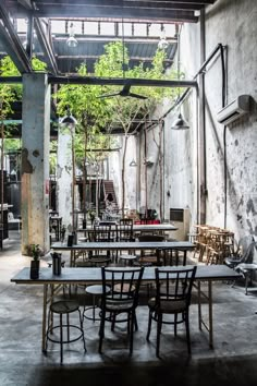 tables and chairs are set up in an industrial setting with exposed ceilings, concrete walls, and steel beams