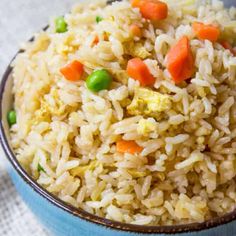 a blue bowl filled with rice and veggies on top of a white table cloth