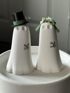 two white ghost figurines sitting on top of a cake