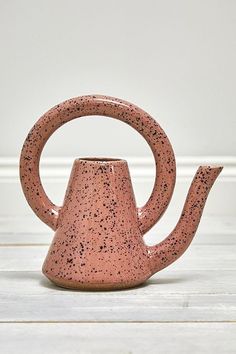 a pink tea pot sitting on top of a wooden table next to a white wall