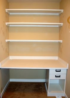 an empty white desk and shelves in the corner of a room with carpeted flooring