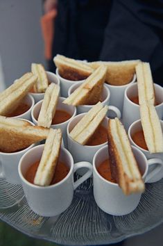 there are many small cups with sandwiches in them on the tray and one is filled with sauces