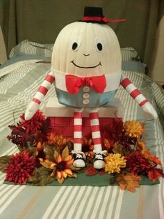 a pumpkin sitting on top of a bed covered in leaves and flowers with a smiling face