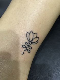 a small tattoo on the ankle of a woman's foot with a flower in it