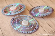 three decorative plates on a wooden table with one white bottle in the middle and two silver ones