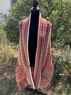 a pink and white crocheted shawl on a mannequin