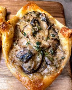 a pizza with mushrooms on it sitting on top of a cutting board next to some bread sticks