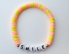 a beaded bracelet with the word smile spelled out in white letters on an orange and yellow string