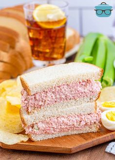 a sandwich cut in half sitting on top of a wooden cutting board next to chips