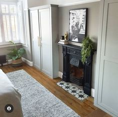 a living room filled with furniture and a fire place next to a window on top of a hard wood floor