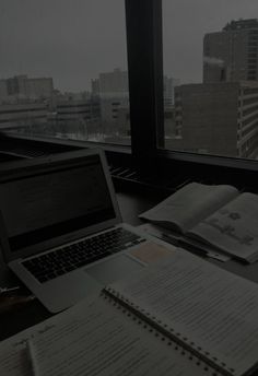 an open laptop computer sitting on top of a desk next to a book and notebook