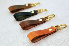 three leather key fobs with gold hardware on them