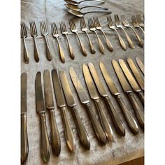 a table topped with lots of silverware on top of a cloth covered tablecloth