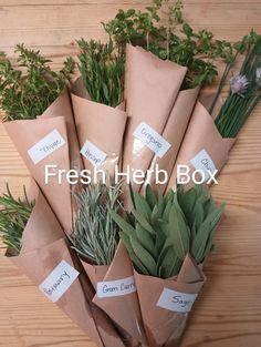 a bunch of herbs wrapped in brown paper on top of a wooden table with the words fresh herb box