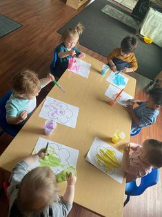 several children sitting at a table with paper cutouts on them and colored pencils