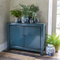 a blue cabinet with plants and vases on top