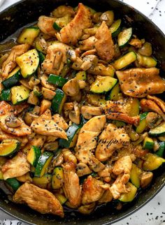 chicken and zucchini stir - fry in a skillet on a marble surface