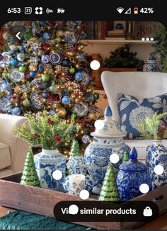 a living room filled with lots of blue and white vases next to a christmas tree