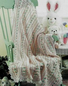 a crocheted blanket sitting on top of a green chair next to stuffed animals