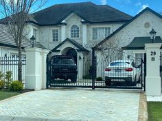 a white car parked in front of a house with a black gate and two driveway gates