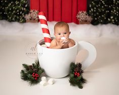 a baby is sitting in a cup with candy canes