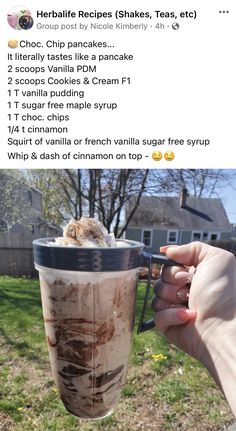 a person holding up a cup filled with ice cream and toppings on top of it