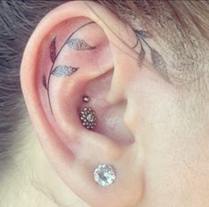 an ear with two piercings attached to it's sides and leaves on the side