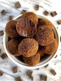 a white bowl filled with chocolate truffles on top of a marble counter