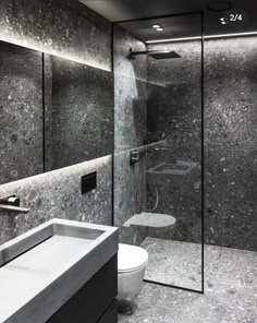 a bathroom with black and white marble walls, a sink, toilet and shower stall