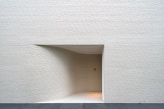 a white brick wall with a small opening in the middle that leads into another room