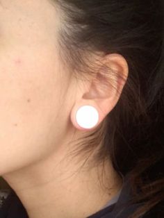 a close up of a person with earring on their ears and wearing a black shirt