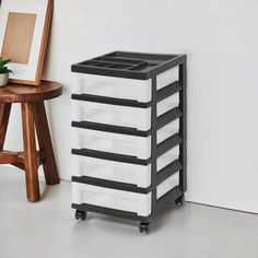 a white and black storage unit next to a wooden table with a potted plant on it