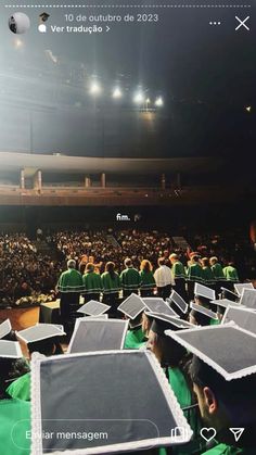 graduates in green caps and gowns are sitting at the end of a lecture hall