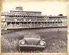 an old car parked in front of a building with a sign that says steel pier, an amusement city at sea