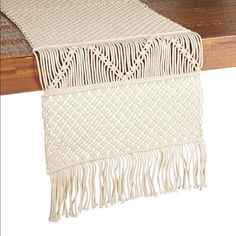 a table runner with fringes on it and a wooden table in the back ground