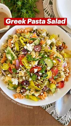 greek pasta salad in a white bowl on a wooden table with the title overlay