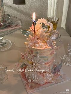 a birthday cake with a lit candle in it sitting on top of a glass plate